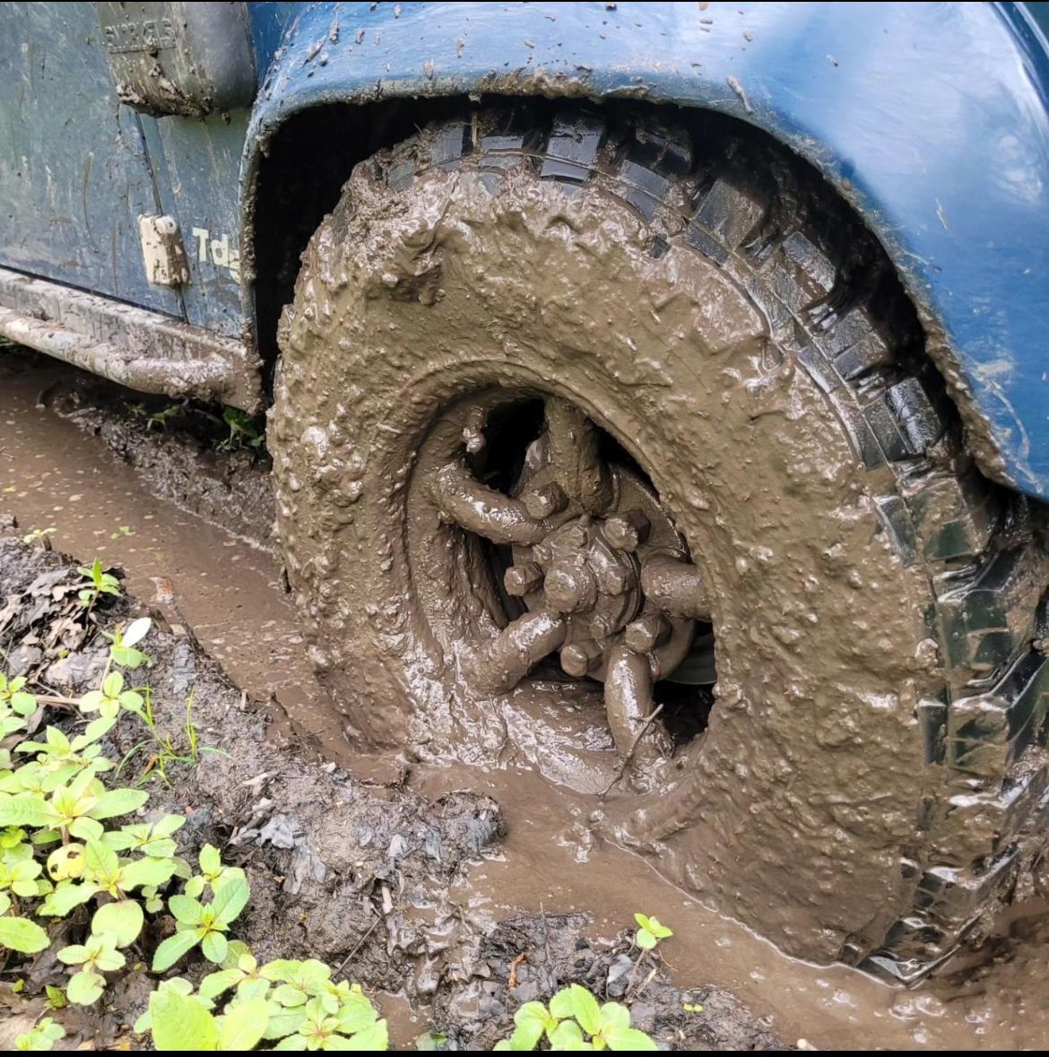 Defender tyre coated in mud on a woodland off-road trail