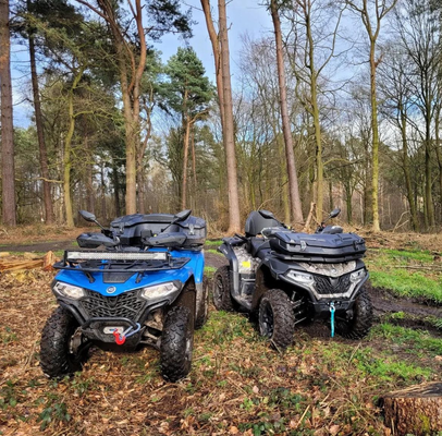 Two quad bikes parked among trees on a forest trail