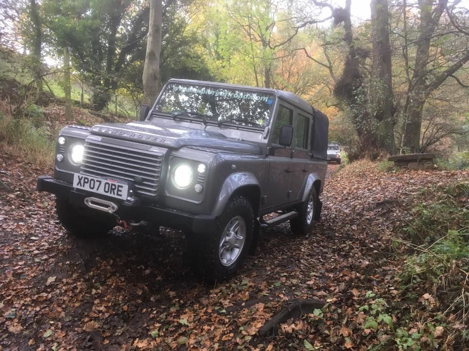 Grey Defender tackling an uneven, leaf-covered woodland track