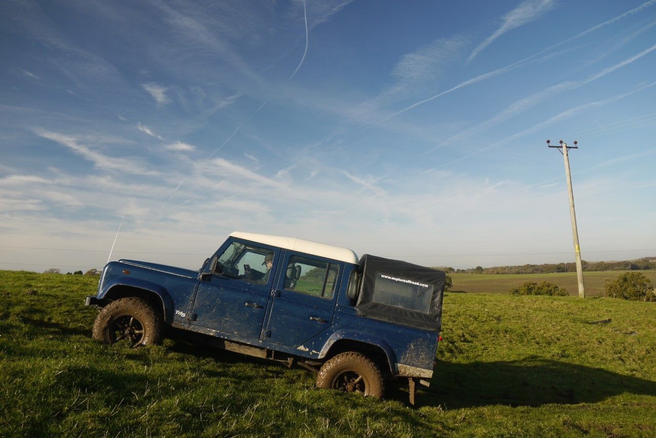 Blue Defender on rolling grassy off-road terrain